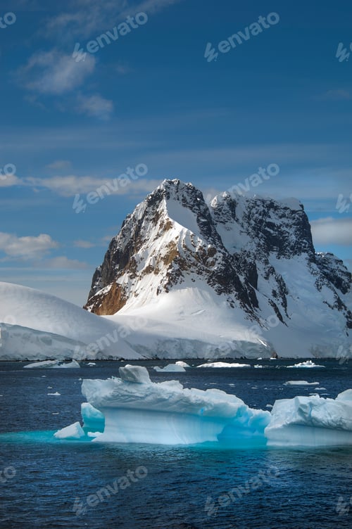 Preview: Icebergs floating in the water off the rocky shore of Antactica.