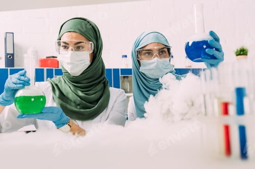Preview: female muslim scientists holding flasks while experimenting with dry ice in chemical laboratory