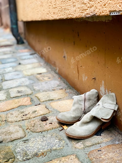 Preview: Old Shoes Standing on Street Paving Stone