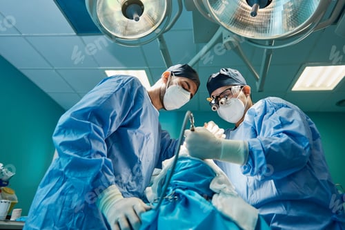 Preview: Surgeon with assistant operating unrecognizable patient in clinic