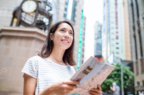 Preview: Young woman using city guide in Hong Kong