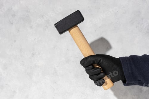 Preview: Construction worker holding a mason's hammer isolated on white textured wall with copy space