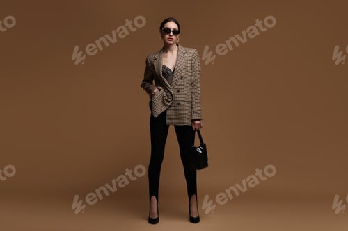 Preview: Full-length portrait of beautiful woman in stylish outfit on brown background
