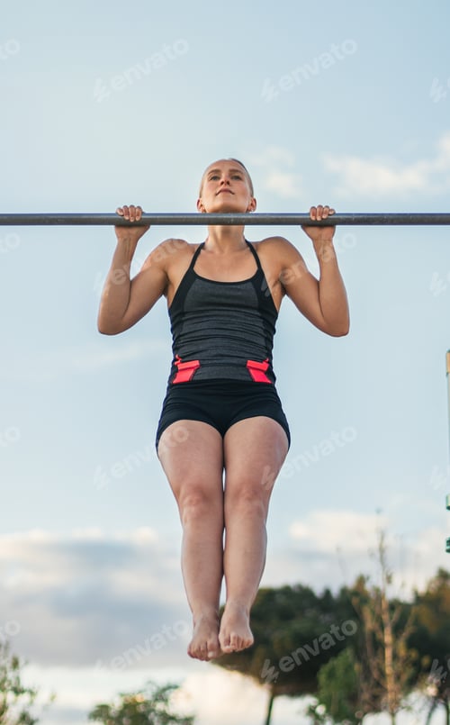 Preview: woman athlete doing pull ups on a bar outdoors. calisthenics