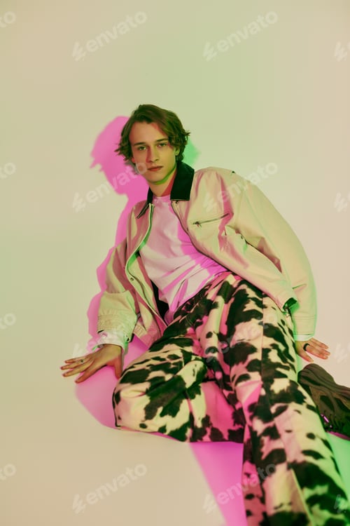 Preview: Young man showcasing modern fashion trends in a vibrant artistic setting full of color and style