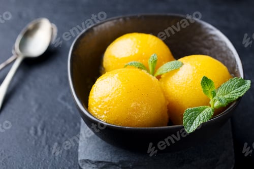 Preview: Mango Ice Cream, Tropical Fruit Sorbet in Black Bowl on Stone Background.