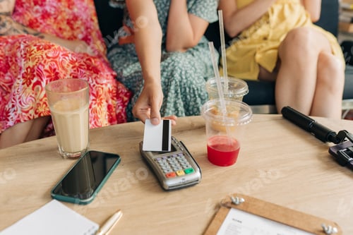 Preview: Close-up of contactless credit card payment by unrecognizable women at cafe