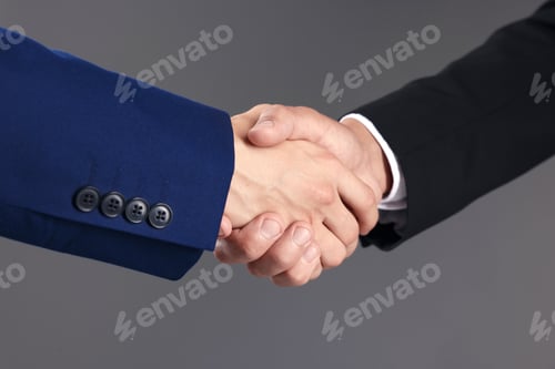 Preview: Business partners shaking hands on grey background, closeup