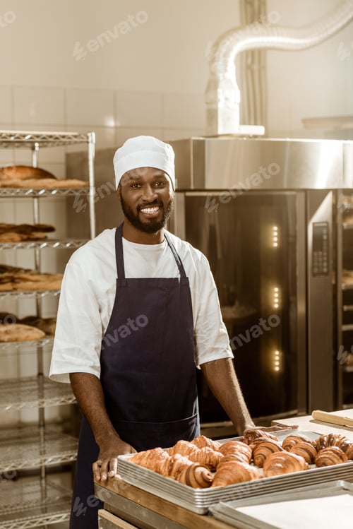 Preview: portrait of handsome african american baker at workplace on baking manufacture