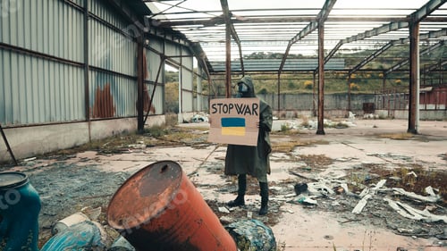 Preview: boy with gas mask holds in hand cardboard with stop war text