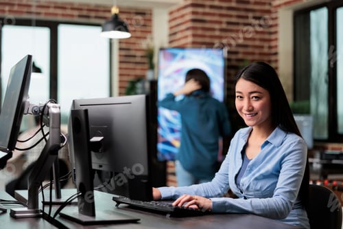 Preview: Smiling 3D artist and developer sitting at desk in office workspace while working on new game