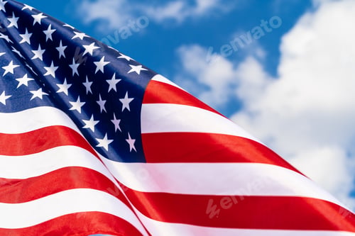 Preview: American flag on flagpole waving in the wind against white clouds