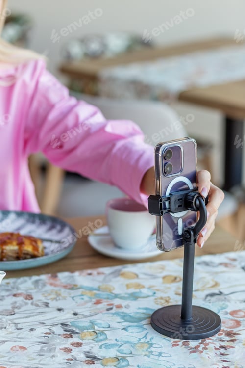 Preview: Woman recording food content on smartphone in cafe