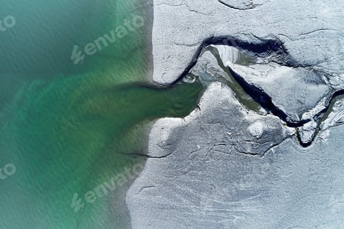 Preview: High angle shot of a huge crack on the stony shore next to the turquoise water