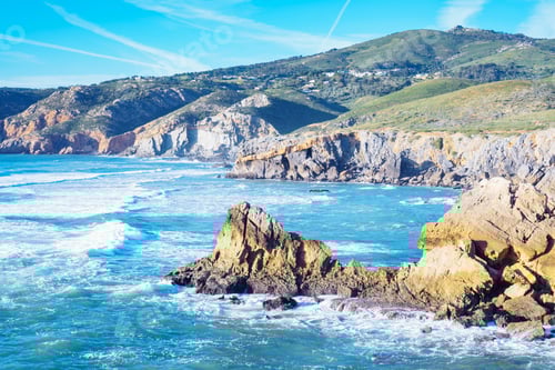 Preview: blue lagoon, rocky seashore coastline, foamy sea waves surrounded by cliffs on windy sunny day.