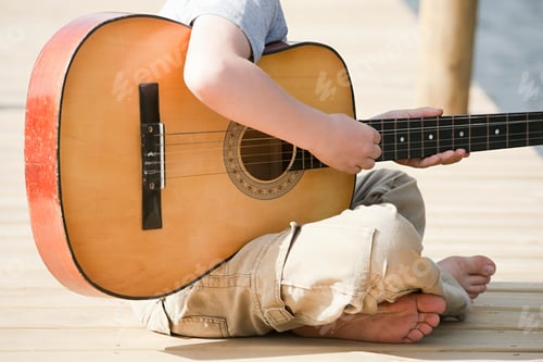 Preview: Little musician playing a big guitar outdoors