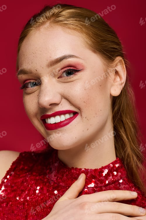 Preview: Captivating young woman smiles brightly against a vibrant red background showcasing her charm
