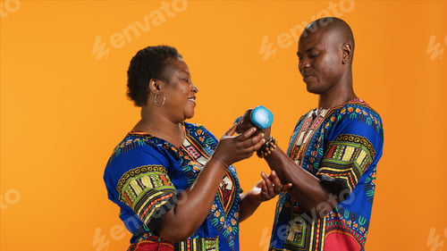 Preview: Joyful woman helping her husband to lift heavy dumbbells