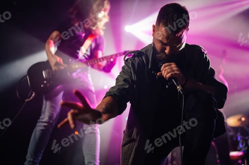 Preview: Singer performing with passion on stage with guitarist in background