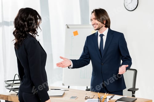 Preview: handsome recruiter gesturing near brunette woman in office