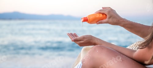 Preview: A woman applies sunscreen on the beach. close up