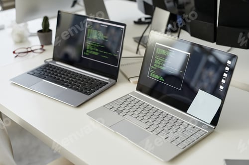 Preview: Two laptop computers with coded data and notepapers on screens
