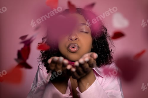 Preview: studio shot in pink color with cute girl blowing confetti. valentine's day concept