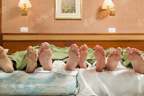 Preview: Four pairs of feet in a bed