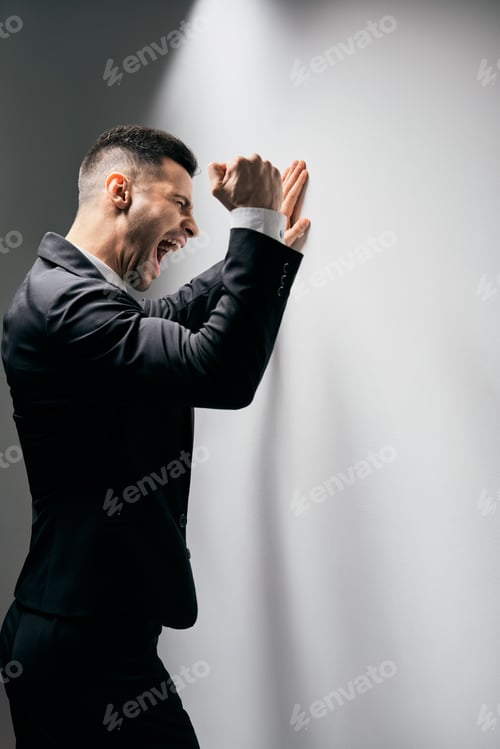 Preview: Stressed despair business man screaming and punching the wall