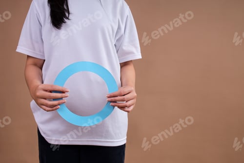 Preview: Woman In White Shirt Holding Large Blue Diabetes Awareness Circle Against Brown Background