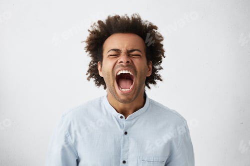 Preview: Portrait of dark-skinned African guy with curly hair screaming with wide opened mouth closing his ey
