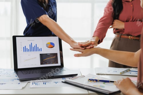 Preview: Businesswomen joining hands over laptop showing positive business performance
