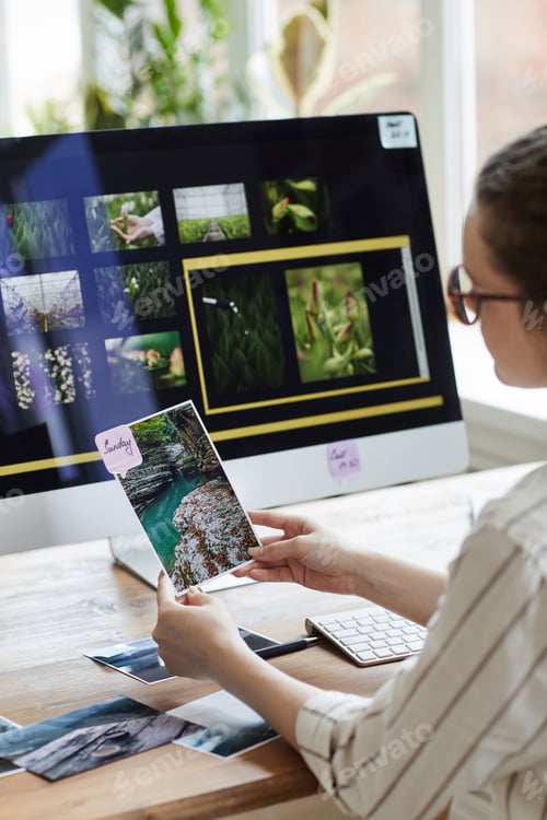 Preview: Female Travel Photographer Holding Picture at desk