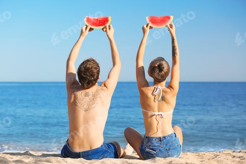 Preview: Young couple with watermelon slices on beach