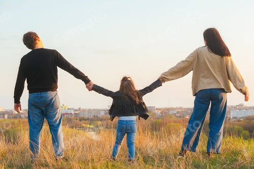 Preview: family with a child on a walk outside the city in the rays of the setting sun