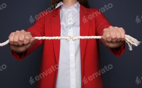 Preview: Woman pulling frayed rope with tension on dark background