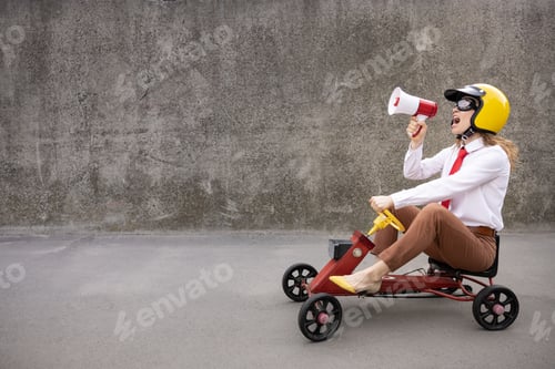 Preview: Funny businesswoman driving retro pedal car outdoor