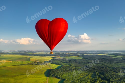 Preview: Red heart-shaped balloon with people over green fields and forests