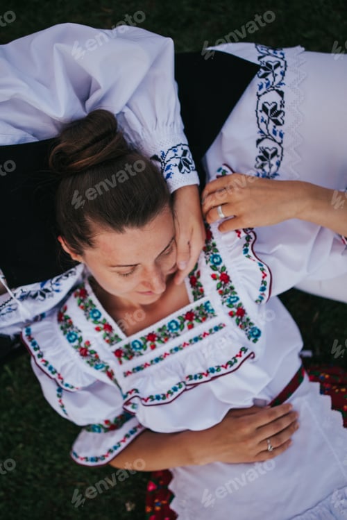 Preview: Couple dressed in traditional Romanian clothes with floral motives relaxing on the grass.
