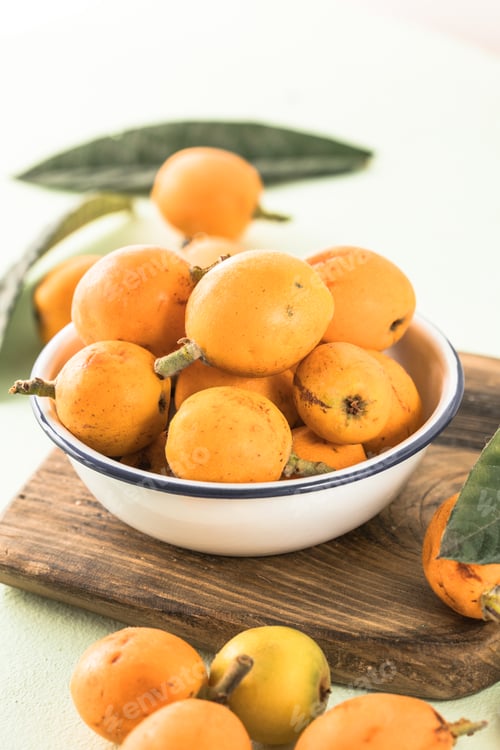 Preview: Ripe medlar fruit , Eriobotrya japonica, and green medlar leaves on wooden table. Top view