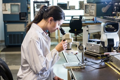 Preview: A caucasian female technician using a microscope in research and development