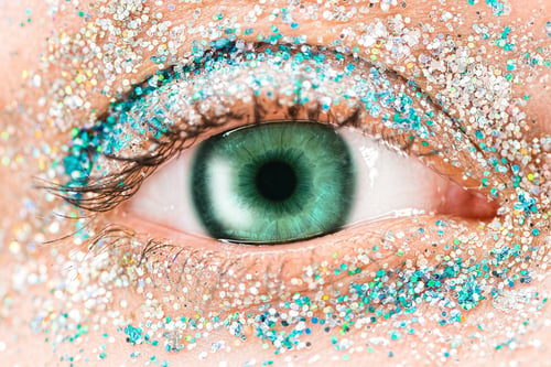 Preview: Macro green female eye with glitter eyeshadow, colorful sparks, crystals. Beauty background, fashion