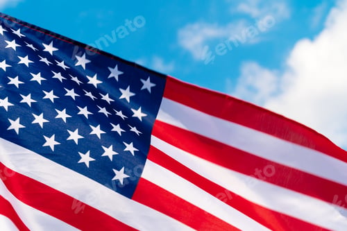 Preview: American flag waving in the wind against blue sky