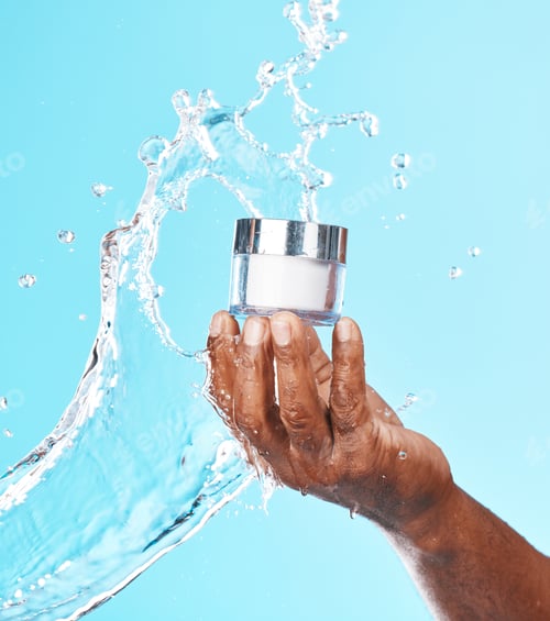 Preview: Hand, water splash and black man with cream for skincare in studio on a blue background. Cosmetics,