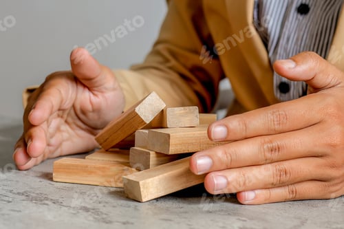 Preview: Businessman Reacting To Falling Blocks, Illustrating Consequences Of Poor Planning