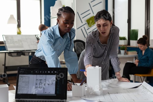 Preview: Team of two professional architects working on blueprints on desk