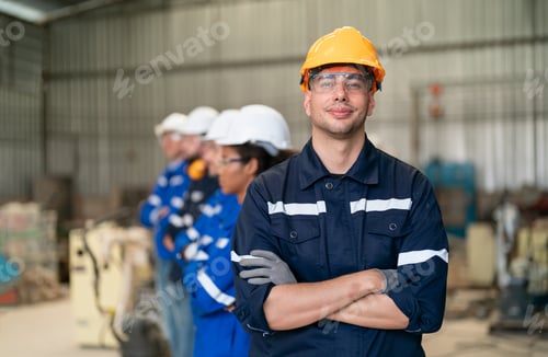 Preview: Young confident leader of team standing in front of factory workers