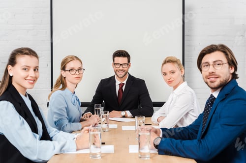 Preview: team of business people sitting at conference hall and looking at camera
