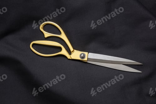 Preview: Overhead of open gold scissors on black cloth. Tailor, fashion and Black Friday sale concept