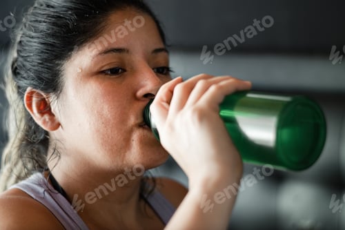 Preview: face of a latina woman sweating the skin of her face while drinking water from her water bottle